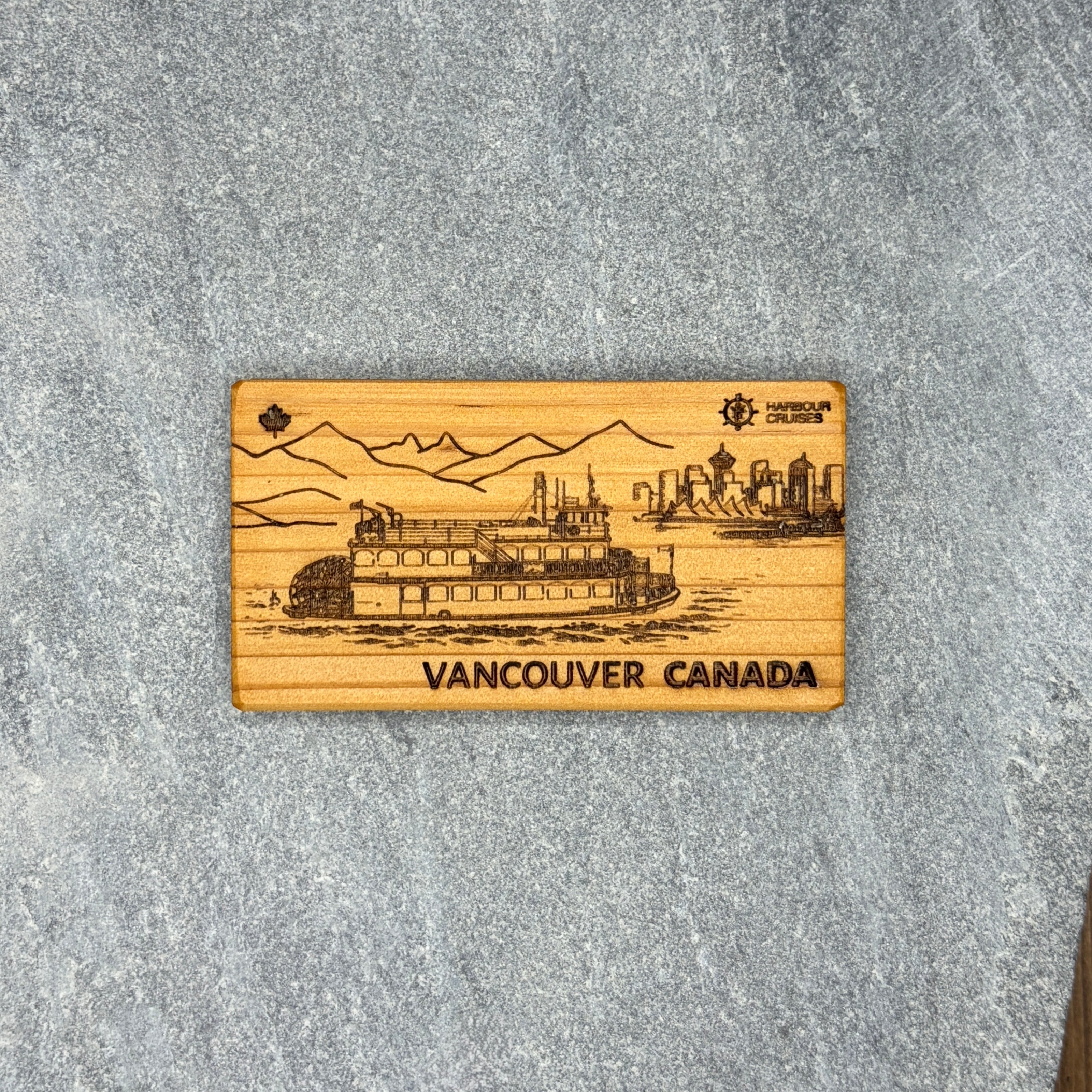 Wooden magnet with engraved image of a steamboat and text 'Vancouver Canada' on a gray surface
