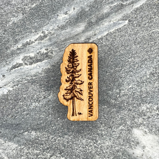 Wooden souvenir magnet with a tree design and 'Vancouver Canada' text on a stone surface