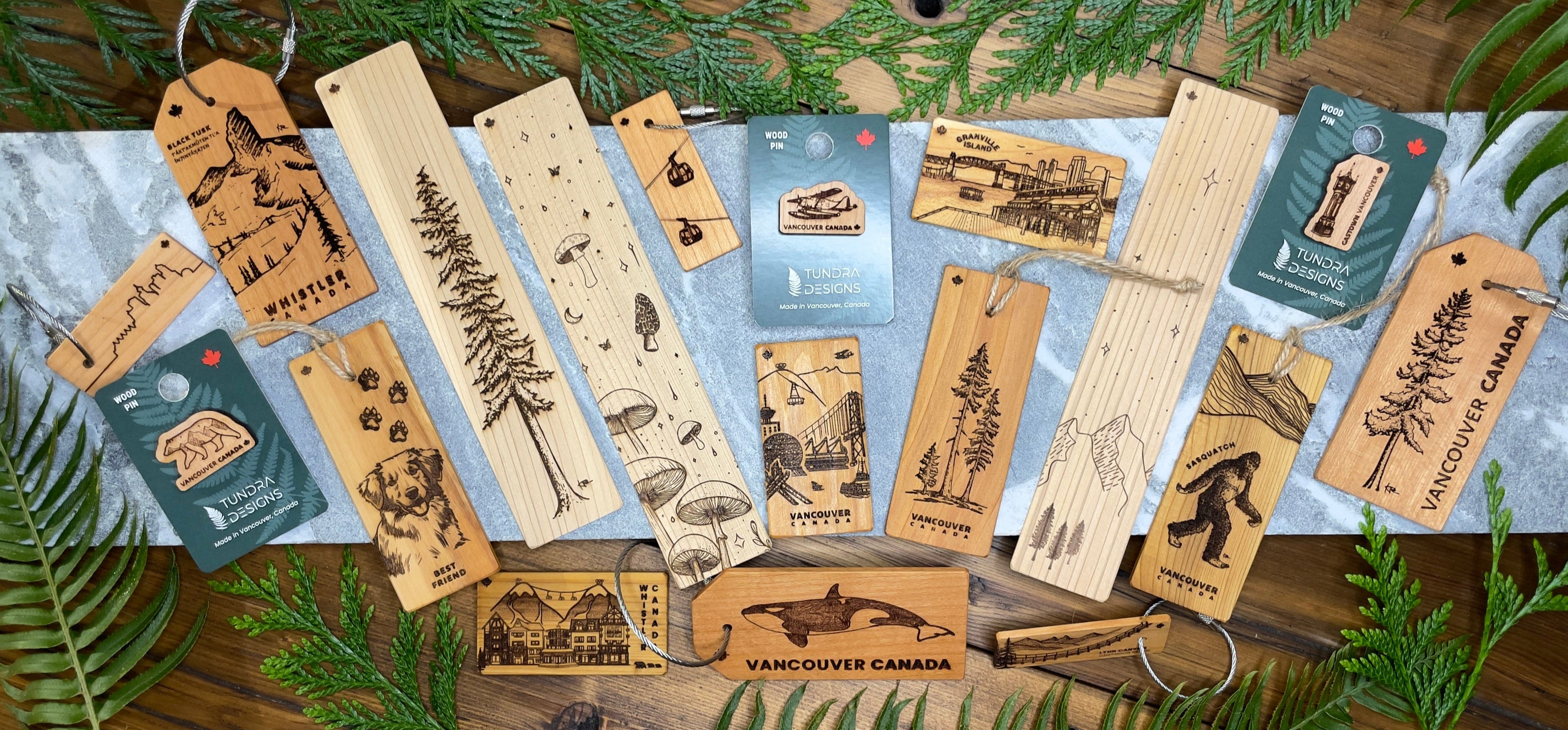 Collection of wooden tags with nature-themed designs on a wooden surface with greenery.