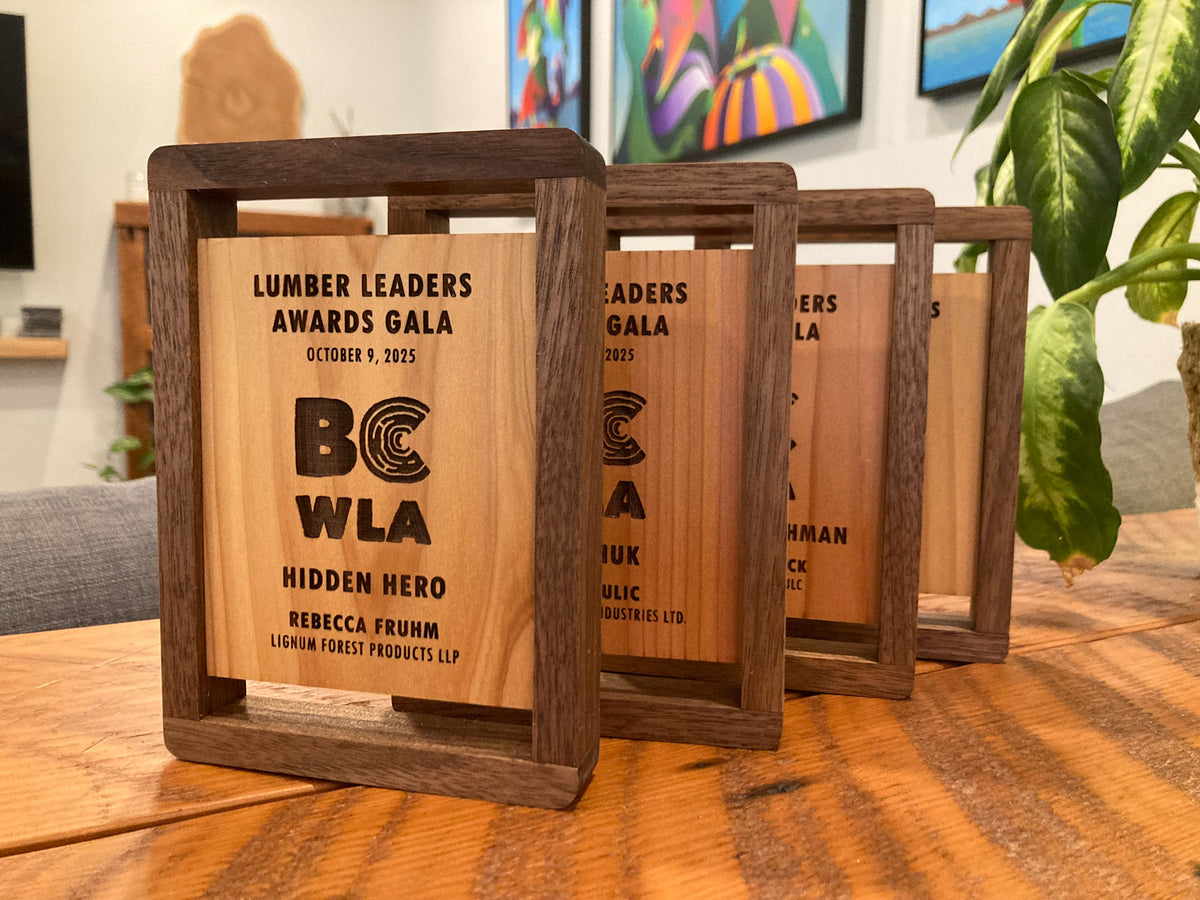 Wooden awards with engraved text on a table, with a blurred indoor background.