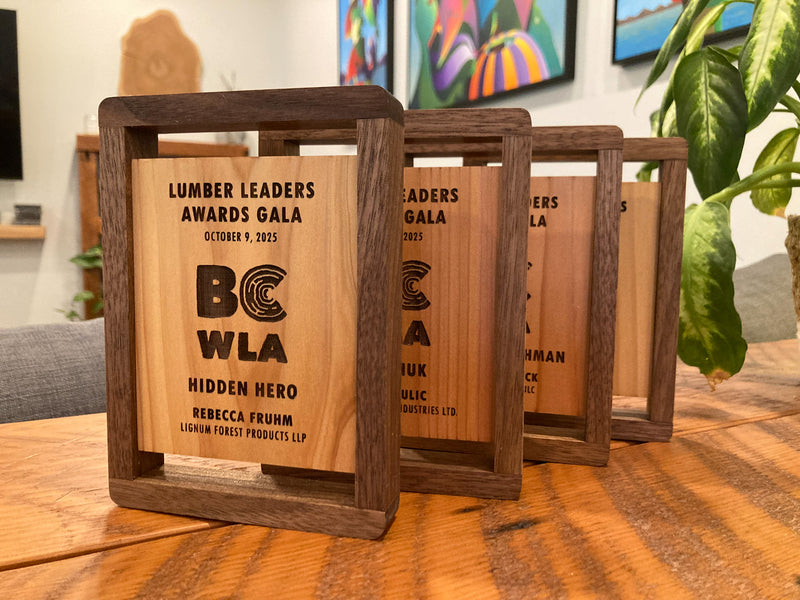 Wooden awards with engraved text on a table, with a blurred indoor background.